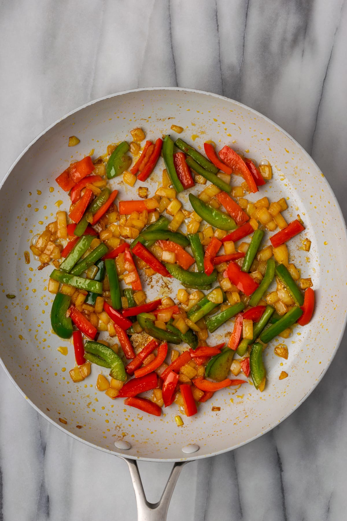 This easy Santa Fe chicken recipe is juicy, tender, rich, and spicy. It only has 6.7 net carbs, and takes just 25 minutes to make. Overhead view of cooked red and green bell peppers, onions, and garlic in a skillet