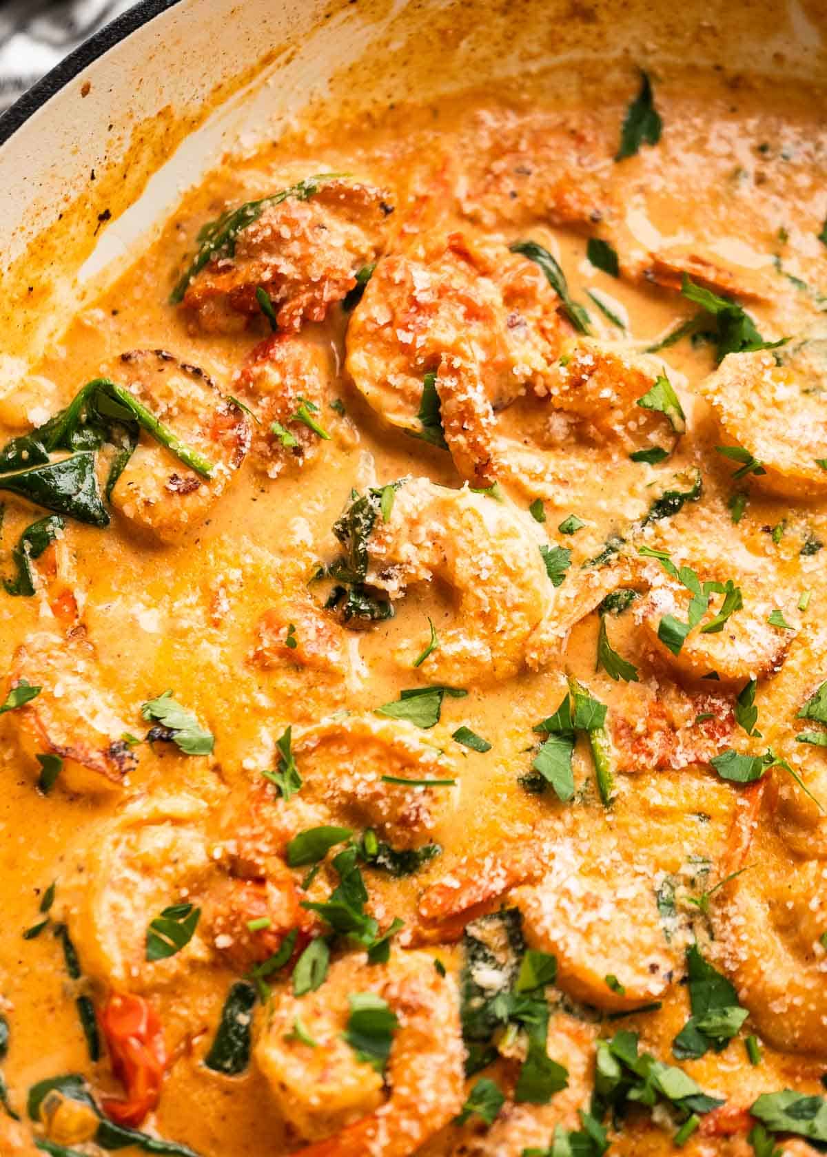 close up image of tuscan shrimp and spoon in pan